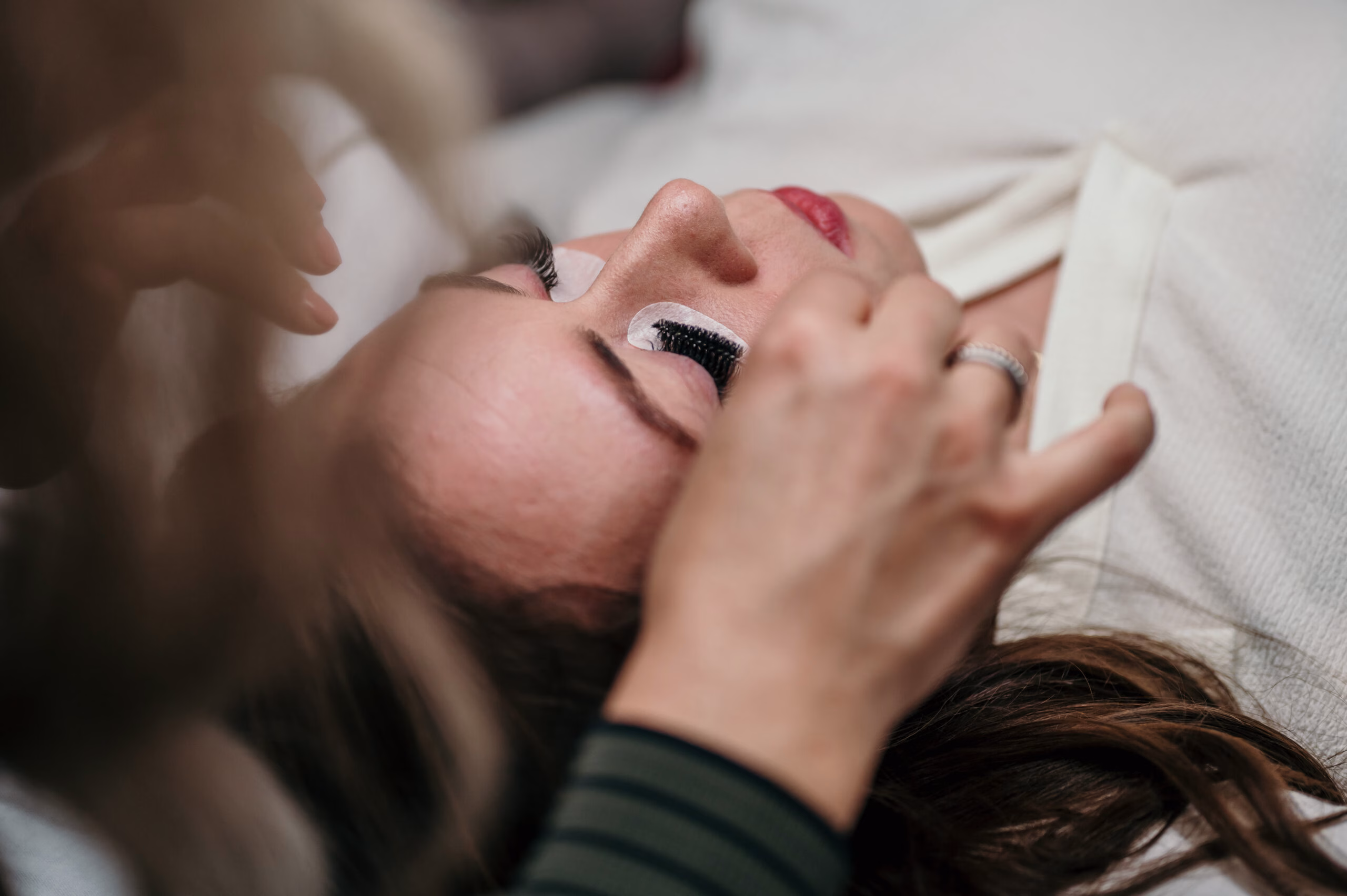 Wimpernverlängerung im Herzwerk Studio: Julia setzt einer Kundin mit geschlossenen Augen Extensions